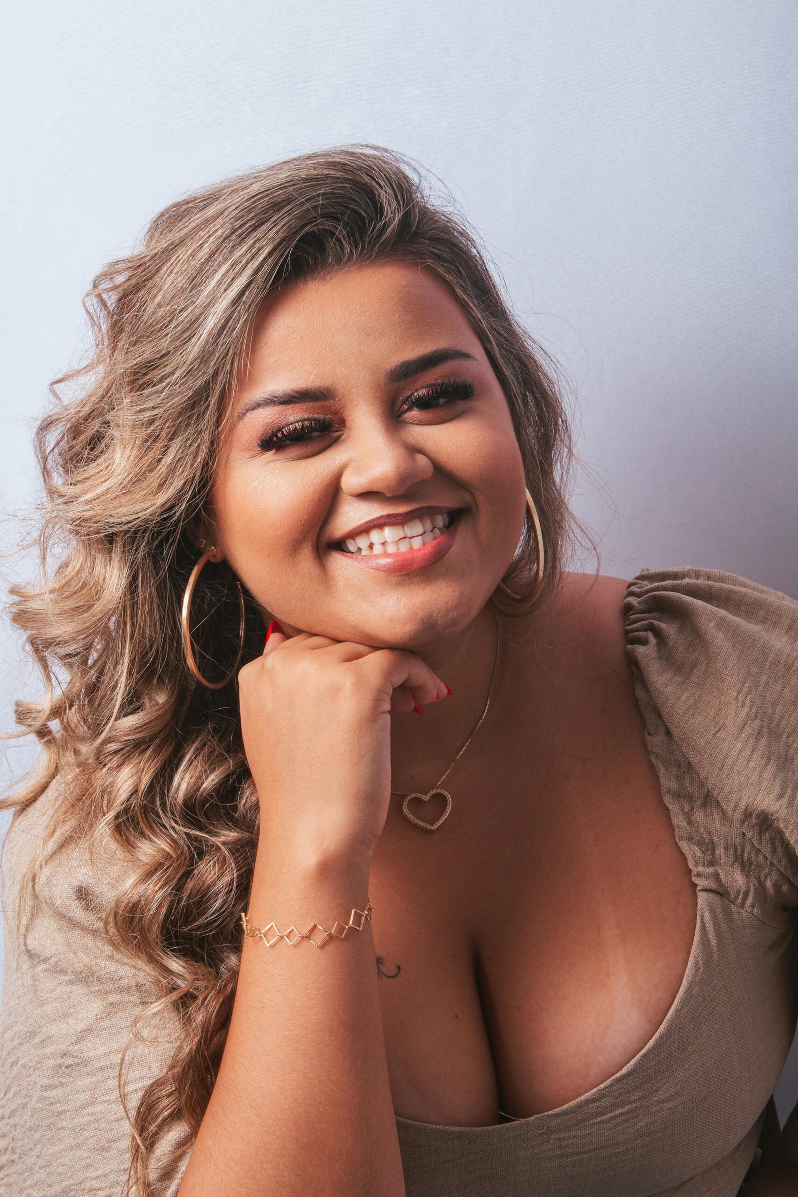 Portrait of a smiling woman with blonde wavy hair posing in a studio against a white background.